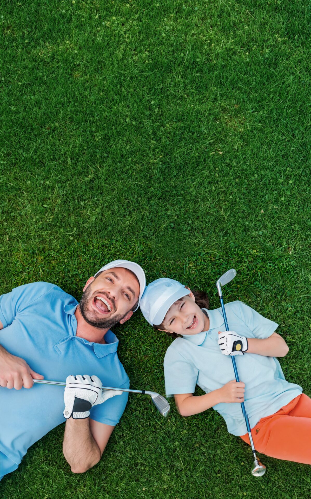 Vater und Kind mit Golfschlägern auf dem Rasen